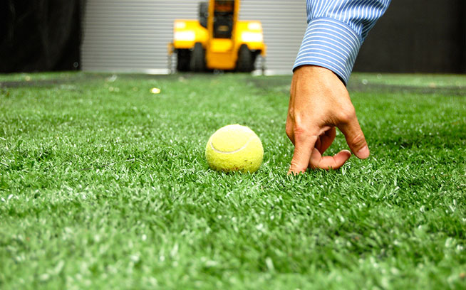 Close-up of a baseball on artificial grass inside an indoor baseball facility